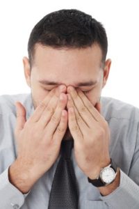 young businessman covering his eyes as if crying,thinking or under extreme stress